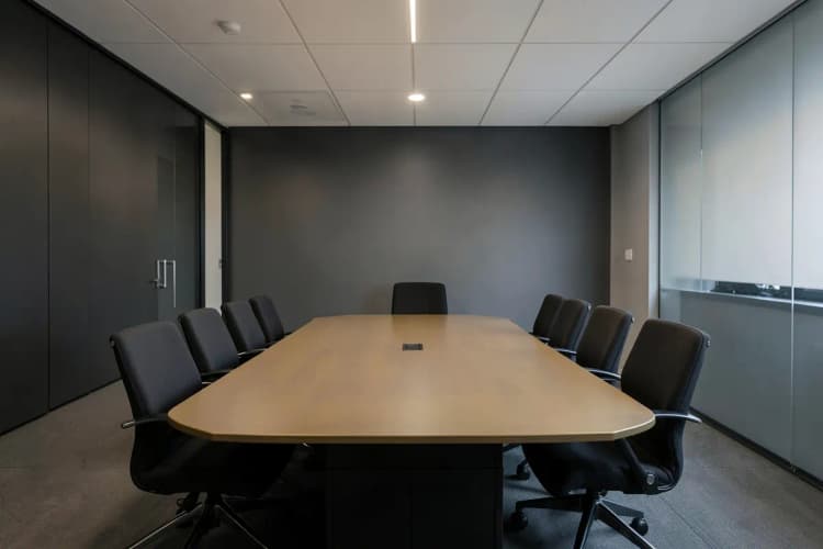 Uma sala de reunião moderna com uma mesa de conferência e cadeiras, com um gráfico de crescimento em uma tela ao fundo.