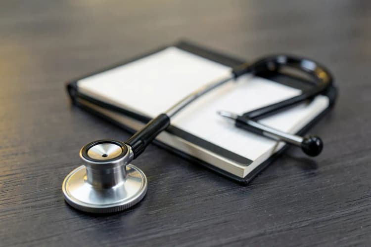 Um close-up de um estetoscópio sobre um prontuário médico em uma mesa de madeira, com luz suave ao fundo.