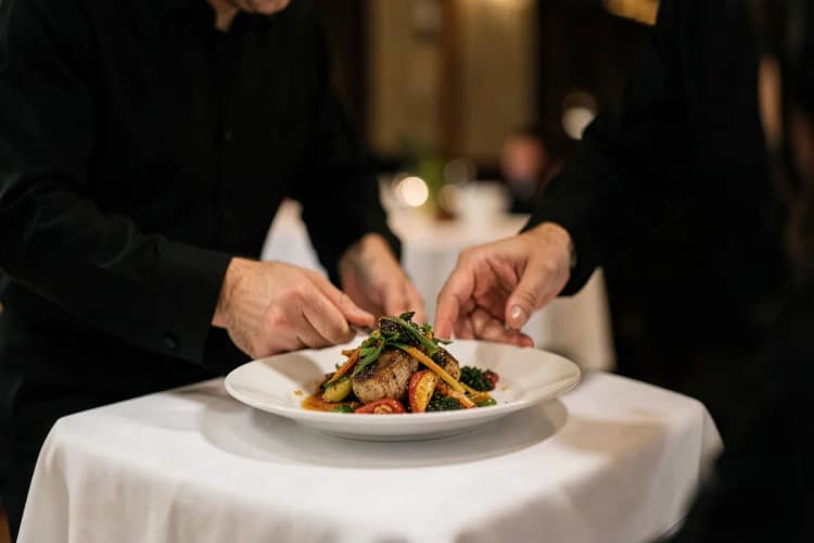 Um garçom atencioso servindo um prato para um cliente em uma mesa de restaurante.