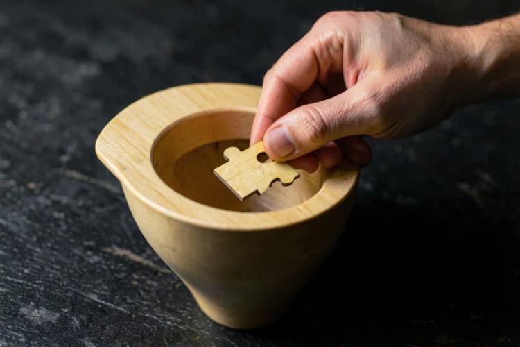 Uma mão colocando uma peça de quebra-cabeça com o símbolo de cliente em um funil de vendas incompleto.
