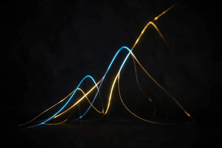 Um gráfico de crescimento abstrato feito de linhas de luz azul e dourada sobre um fundo escuro.