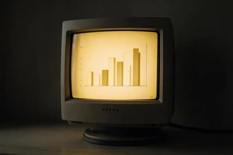 Um computador antigo exibindo um gráfico de barras simples em sua tela, com luz suave vindo da tela.